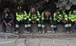 Des secouristes épuisés prennent une pause dans la recherche des survivants, le 5 juin 2018.