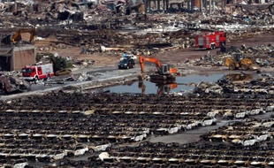 Des véhicules de secours interviennent près de rangées de voitures carbonisées sur le site des explosions de Tianjin, en Chine, le 16 août 2015