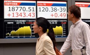 Des passants regardent un tableau d'indices boursiers, le 9 septembre 2015 à Tokyo