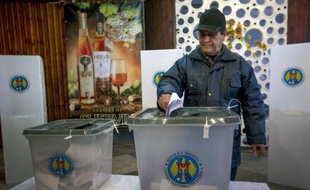 Un homme glisse son bulletin de vote dans une urne, le 30 novembre 2014 à Chisinau lors des législatives en Moldavie