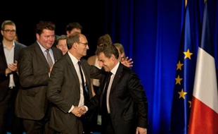 Nicolas Sarkozy (C) salue l'ancien ministre du budget Eric Woerth (G), lors d'un meeting le 9 avril 2015 à Gouvieux dans le nord-est de Paris