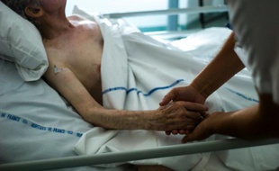Une infirmière tient la main d'un patient dans une unité de soins palliatifs d'Argentueil, le 22 juillet 2013