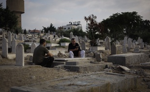 Un père et un fils palestiniens sur la tombe d'un autre fils, mort après une attaque israélienne dans la bande de Gaza, le 28 juillet 2014.