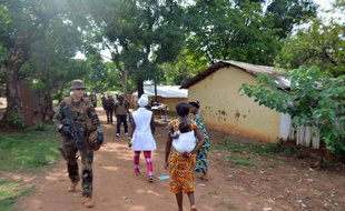 Une centrafricaine portant un bébé passe devant des soldats français de l'opération Sangaris en patrouille à Bangui le 20 mai 2015