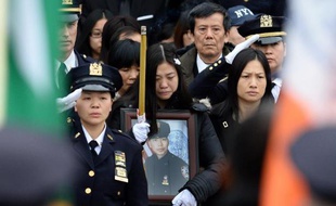 Pei Xia Chen (c), veuve du policier assassiné Wenjian Liu, brandit son portrait lors de ses funérailles à New York le 4 janvier 2015