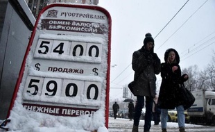Des passants marchent devant un bureau de change dans une rue du centre de Moscou, le 12 décembre 2014