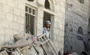 Un homme observe les dégâts causés par un raid aérien de la coalition, à Sanaa, le 1er mai 2015