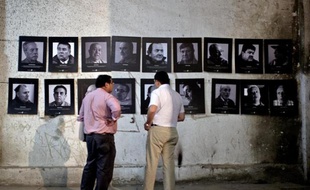 Des membres de l'association des Anciens Prisonniers Politiques du Stade National regardent des photos de la période de la dictature de Pinochet exposées dans le stade, le 10 février 2015 à Santiago