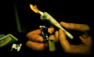 Une personne allume un joint
