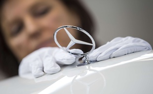 Une femme fixe le logo de Mercedes sur une voiture (image d'illustration).