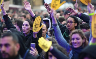 Des manifestants arborant es mains flanquées du slogan