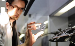 Un employé contrôle un verre avant de lui appliquer un traitement anti-reflets, au laboratoire d'Essilor, à Ligny-en-Barrois (Meuse), le 19 janvier 2015