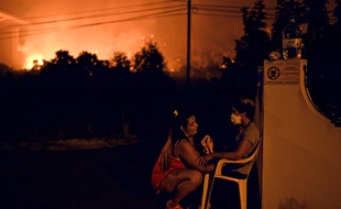Les incendies font rage au Portugal. Une femme tente de rassurer son voisin.