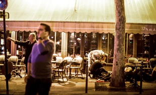 Des personnes s'occupent d'une personnes allongée au sol après les tirs qui ont visé le café «La bonne bière», le 13 novembre 2015