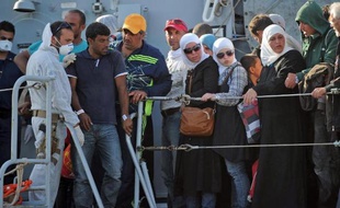 Des familles de migrants débarquent d'un navire militaire italien, en Sicile, après avoir été secourus en mer, le 30 juin 2014