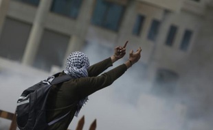 Un Palestinien fait un geste d'insulte envers des soldats israéliens à Beit El (Cisjordanie), le 8 octobre 2015