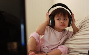 Un enfant devant la télévision, un casque sur les oreilles.