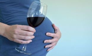 Une femme enceinte tenant un verre d'alcool à la main (illustration).