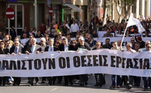 Employees of the bank hold banners as they march towards the parliament on April 4, 2013 during a demonstration in the Cypriot capital, Nicosia, over fears that pensions may be at risk under Cyprus's bailout, as more details emerged of biting austerity measures imposed on the cash-strapped island. Bank employees' union ETYK called the two-hour work stoppage over concerns that pension funds at failed Laiki and at Bank of Cyprus are not being protected under the island's 10-billion-euro bailout deal with the IMF, European Commission and European Central Bank. AFP PHOTO / PATRICK BAZ