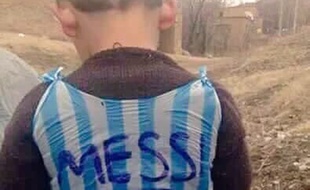 La photo d'un enfant avec un maillot de Lionel Messi fabriqué à partir d'un sac plastique.