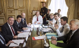 Photo du 11 avril 2014 montrant le Premier ministre Manuel Valls (gauche) entouré de ses ministres, face au patron des patrons Pierre Gattaz (d) et au vice-président du Medef Geoffroy Roux de Bezieux à Matignon