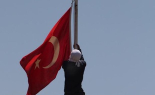 Un militant kurde masqué essaie de décrocher un drapeau turc à Diyarbakir, à l'Est de la Turquie, le 8 juin 2014