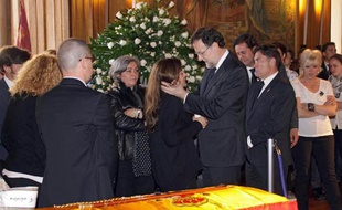 Le Premier ministre espagnol Mariano Rajoy (au centre droit) tient dans ses bras, le 13 mai 2014, la fille de la dirigeante locale du parti conservateur assassinée la veille à Leon