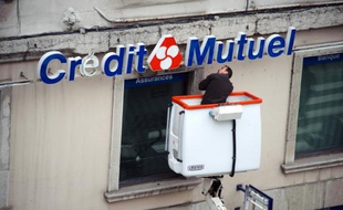 Un technicien répare l'enseigne d'une agence bancaire du Crédit Mutuel, le 10 mars 2009 dans le centre ville de Lyon