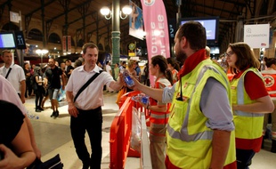Des membres de la Croix Rouge distribuent de l'eau aux voyageurs coincés dans la soirée à la Gare du Nord, le 19 juillet 2016 à Paris