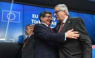 Le Premier ministre turque Ahmet Davutoglu (g), salue le président de la Commission européenne Jean-Claude Juncker, lors d'une conférence de presse à la fin d'un sommet entre l'Union européenne et la Turquie, à Bruxelles, le 29 novembre 2015