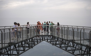 Une passerelle au plancher en verre emmène les touristes à plus de 120 mètres au-dessus du vide, au bord d'une falaise du sud-ouest de la Chine.