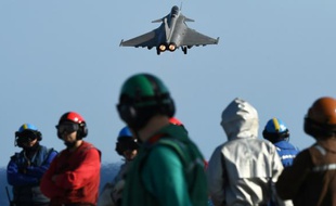 Des militaires français sur le pont du Charles de Gaulle regardent un rafale partir pour bombarder au-dessus des zones contrôlées par le groupe Etat islamique (EI) en Irak et Syrie le 23 novembre 2015