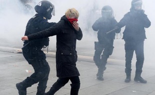 Un policier anti-émeutes arrête une manifestante durant des heurts violents à Pristina le 27 janvier 2015