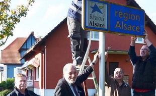 Le maire et des conseillers municipaux démontent le panneau région Alsace, pour le nettoyer