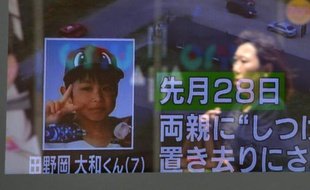 Un piéton passe devant un écran de télévision montrant le petit garçon disparu au Japon, le 3 juin 2016