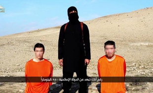 Capture d'écran d'une vidéo diffusée le 20 janvier 2015 par le média du groupe Etat islamique Al-Furqan montrant un membre de l'EI près de deux otages japonais dans un endroit non localisé