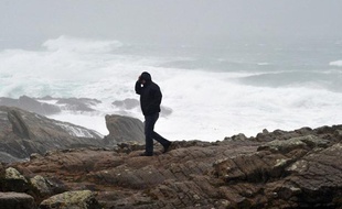 Un homme marche près de la mer, à Saint-Guénolé, dans le Finistère, alors que la Bretagne est touchée par des vents violents, le 23 décembre 2013.