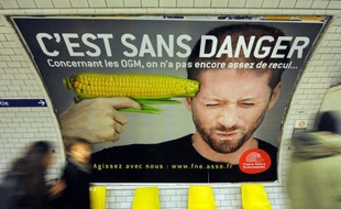 Des gens passent devant l'affiche d'une campagne contre les OGM menée par l'association France Nature Environnement, le 15 février 2011 dans le métro parisien