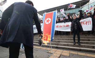 Des Coréens du Sud brûlent un drapeau de la Corée du Nord pour protester contre le rapprochement entre les deux nations à l'occasion des JO d'hiver 2018.