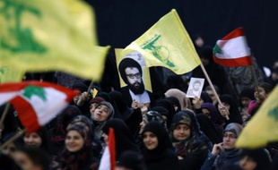 Des partisans brandissent des drapeaux du Liban et du Hezbollah ainsi qu'une affiche de l'ancien leader du mouvement chiite libanais Abbas Moussaoui, le 16 février 2016 à Beyrouth