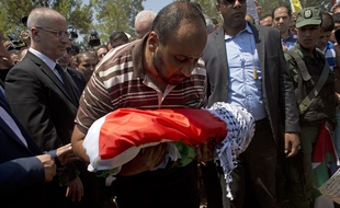 Un membre de la famille tient le corps du bébé Palestinien de 18 mois tué dans un incendie criminel, pendant son enterrement le 31 juillet 2015 dans le village de Duma, en Cisjordanie.