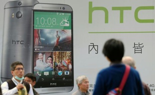 Des gens passent devant la publicité du dernier smartphone de HTC, le 6 janvier 2015 à Taipei