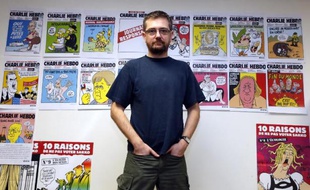 Le dessinateur Charb pose devant les Unes de Charlie Hebdo, dont il était le directeur, le 27 décembre 2012, le jour où il présentait à la presse un album intitulé "La Vie de Mahomet"