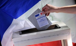 Une personne insère un bulletin de vote dans un urne