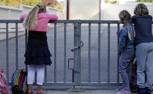 Des enfants attendent devant les grilles fermées de Ganzeville en Normandie, le 10 septembre 2014