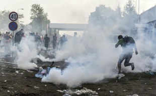 Des réfugiés courent pour se protéger des gaz lacrymogènes à la frontière serbo-croate près de la ville de Horgos, le 16 septembre 2015