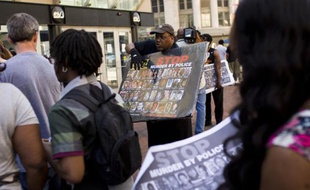 Des assistants à un concert de Prince en faveur de la paix portent des affiches appelant à mettre un terme aux bavures de la police américaine, le 10 mai 2015 à Baltimore, dans l'Etat de Maryland