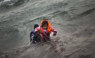 A man carries a child as they try to reach a shore after falling into the sea while disembarking from a dinghy on which they crossed a part of the Aegean sea with other refugees and migrants, from Turkey to the Greek island of Lesbos, on Sunday, Jan. 3, 2016. More than a million people reached Europe in 2015 in the continent's largest refugee influx since the end of World War II. Nearly 3,800 people are estimated to have drowned in the Mediterranean last year, making the journey to Greece or Italy in unseaworthy vessels packed far beyond capacity. (AP Photo/Santi Palacios)/XYK112/4712433725/1601031755