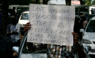 Une pancarte sur laquelle on peut lire "Dernier avertissement Nkurunziza, cessez de tuer des gens, nous en avons assez de votre mauvais gouvernement", brandie par un manifestant lors des funérailles d'un journaliste à Bujumbura le 20 octobre 2015