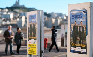 People walk by electoral posters for the upcoming regional elections in Marseille on November 30, 2015. AFP PHOTO / BORIS HORVAT